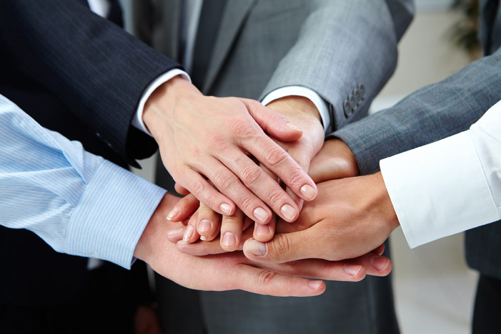 Mitarbeiter legen die Hände aufeinander - Teamwork