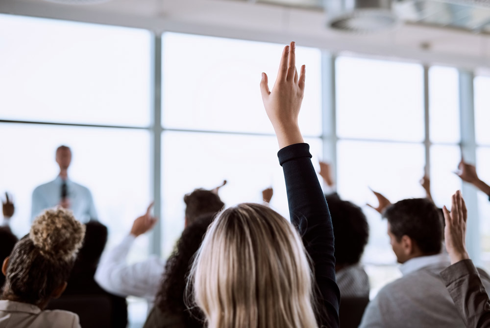 Frau hebt die Hand während einer Konferenz