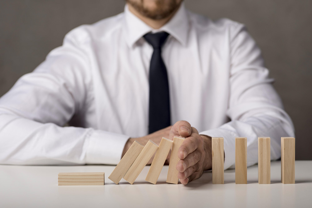 Geschäftsmann hält das Umfallen der Dominosteine auf